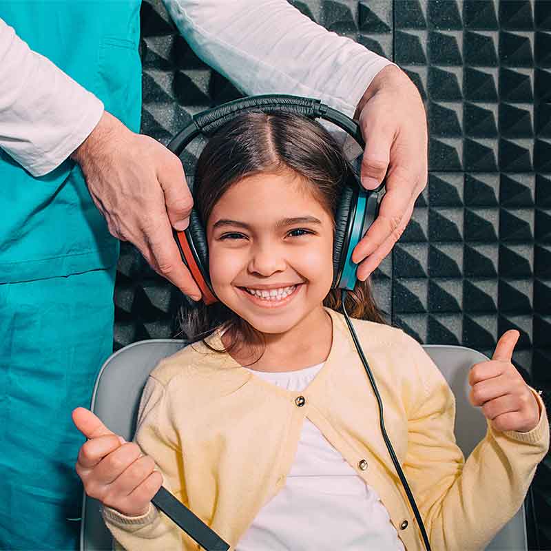Young girl in a hearing booth having her hearing tested.